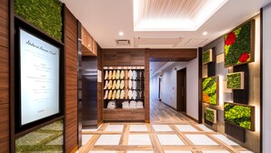 A hotel lobby with a wooden floor, a wall-mounted shoe rack, and a vertical garden display. - Super Hotel Nagano Iida Inter (Iida)