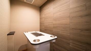 A modern bathroom with a wooden panel wall, a white pedestal sink, and a ceiling vent.