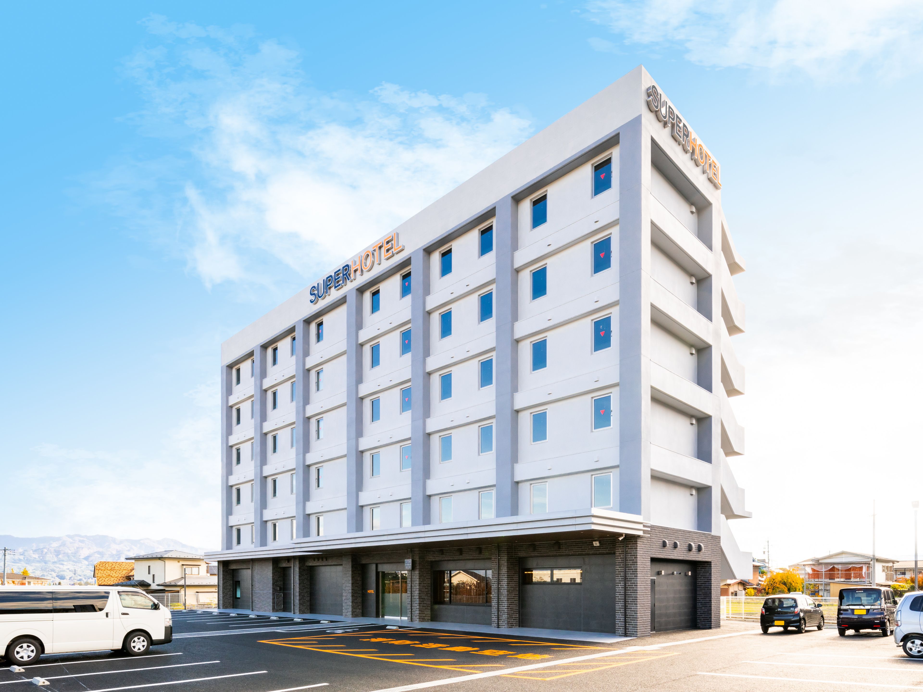 A modern hotel with a flat facade, multiple windows, and a sign reading "Super Hotel".