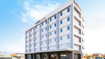 A modern hotel with a flat facade, multiple windows, and a sign reading "Super Hotel".