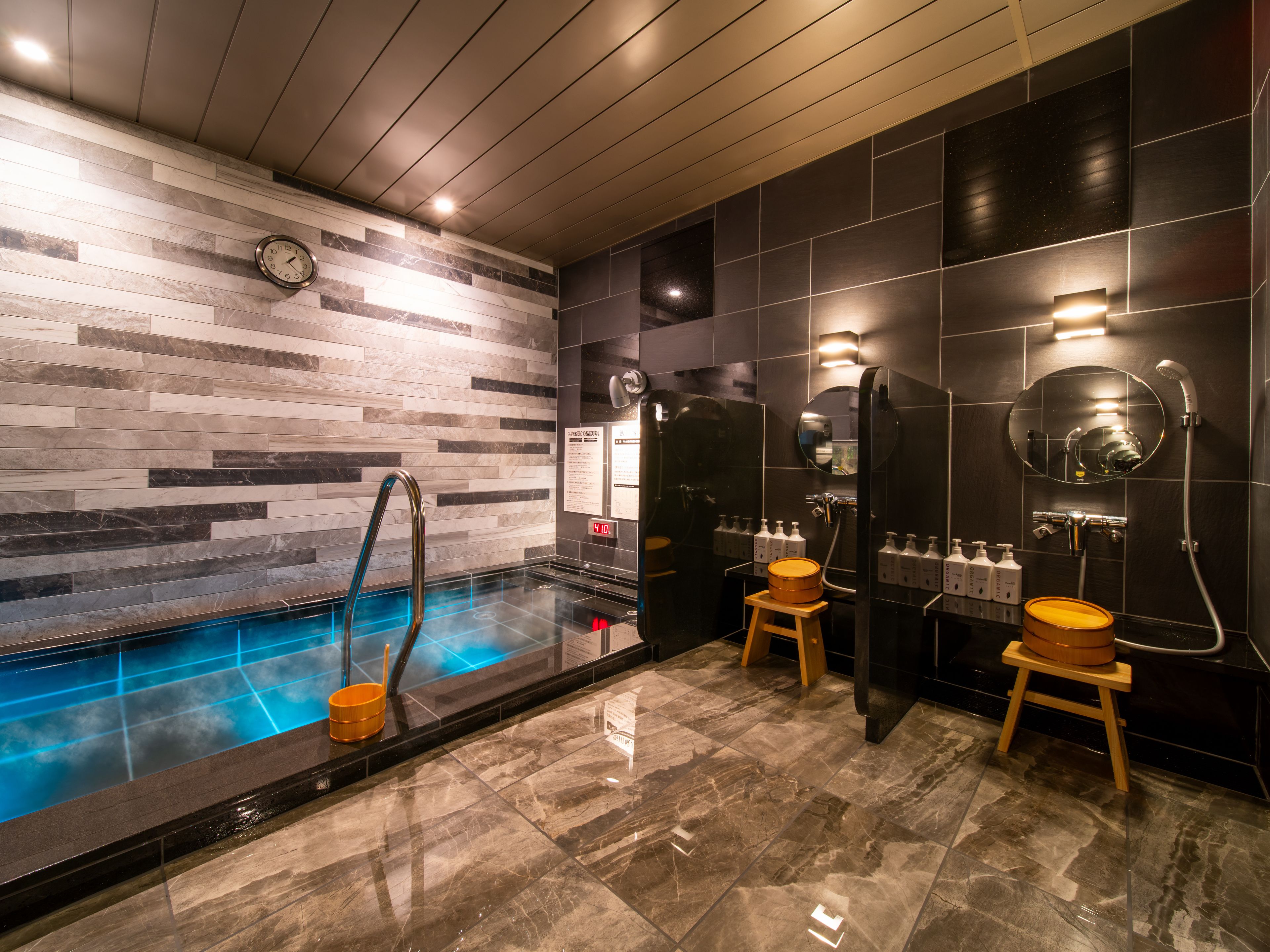 A modern bathroom with a marble floor, a built-in hot tub, and a shower area with a mirror and toiletries.