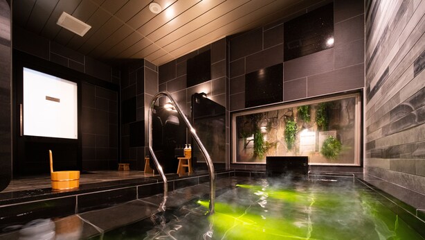 A modern spa with a heated floor, a wooden bucket, and a large window with plants. - Super Hotel Nagano Iida Inter (Iida)