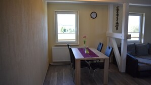 Ein Essbereich mit einem Holztisch, Stühlen, einer Blumenvase und einer Uhr an der Wand.