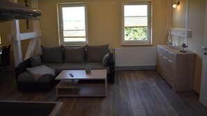 Ein gemütlicher Wohnbereich mit Sofa, Couchtisch und einer kleinen Küchenzeile.