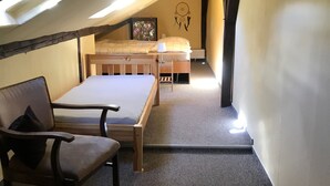 Ein gemütliches Schlafzimmer im Dachgeschoss mit einem Etagenbett, einem Holztisch und einem Stuhl.