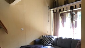 Ein Wohnzimmer mit einem grauen Ecksofa, einem kleinen runden Tisch und Holzboden.