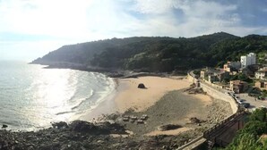 Un pueblo costero con una playa de arena, un litoral rocoso y edificaciones a lo largo de la costa.