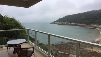 A balcony with a view of the sea, a table, and two chairs.