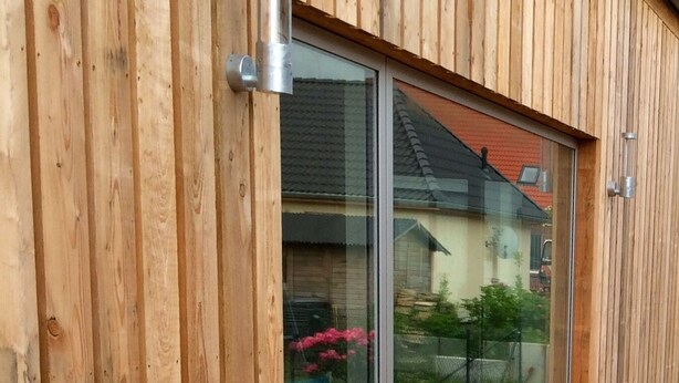 A wooden exterior with a sliding glass door leading to a deck.