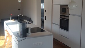 A compact kitchen with a central island, a microwave, oven, and hanging pendant lights.