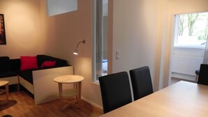 Ett modernt vardagsrum med en soffa, ett litet runt bord och ett matbord med stolar.