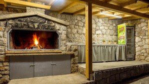 A stone fireplace with a fire, a stone wall, and a wooden ceiling. - New villa for 6 persons with private pool and sea view (Smokvica Krmpotska/Klenovica)