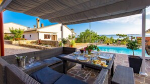 A covered outdoor seating area with wicker furniture, a pool, and a view of the sea. - New villa for 6 persons with private pool and sea view (Smokvica Krmpotska/Klenovica)
