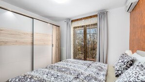 A bedroom with a bed, a window with curtains, a wardrobe, and an air conditioning unit. - New villa for 6 persons with private pool and sea view (Smokvica Krmpotska/Klenovica)