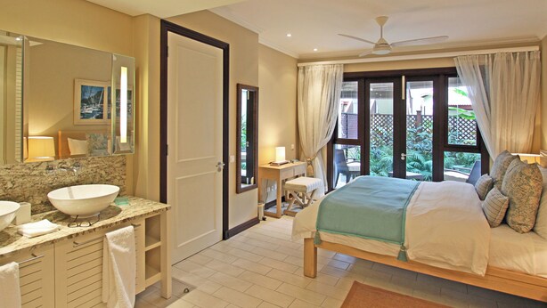 Une chambre d’hôtel avec un grand lit, une salle de bain avec un lavabo et un miroir, et une vue sur l’extérieur.