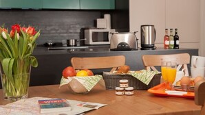 A breakfast setup with a tray of eggs, toast, and juice, a vase of tulips, and a newspaper on a wooden table.