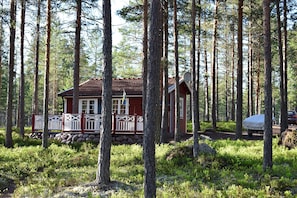 Eine Hütte mit roter Fassade und weißer Verzierung, umgeben von hoch aufragenden Kiefern.