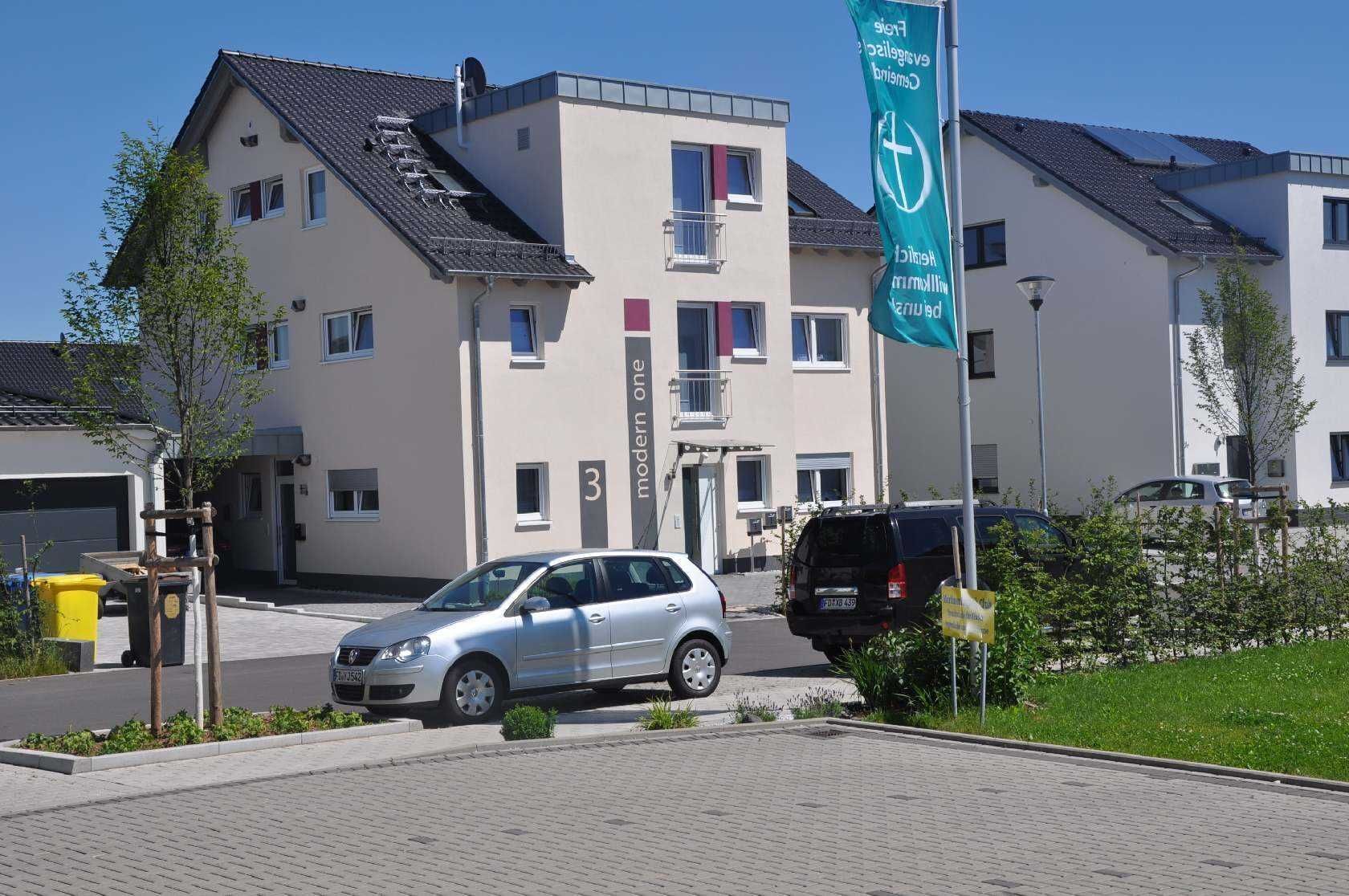A modern building with a flat roof, solar panels, and a flag indicating a green initiative.