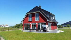 A red house with a sloped roof, large windows, and a satellite dish.