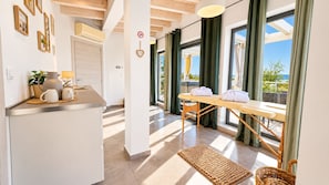 A modern kitchen with a dining area, large windows, and a view of the outdoors.