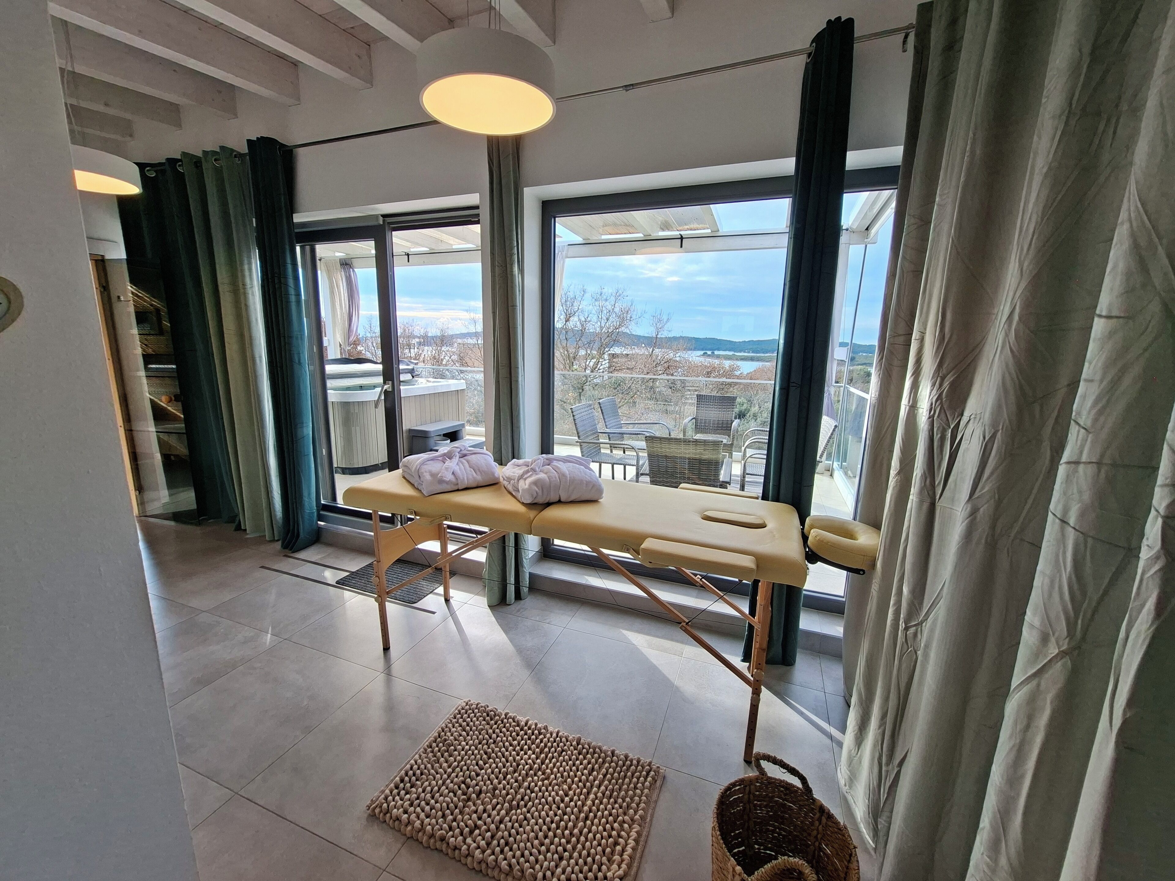 A room with a massage table, large windows, and a view of the city.