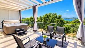 Ein Balkon mit Whirlpool, Sitzgelegenheit und Blick auf Grünflächen und Wasser.