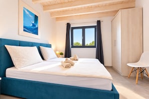 A hotel room with a bed, a chair, a window, and a painting on the wall.