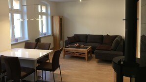 Ett modernt vardagsrum med en matplats, en soffa, ett soffbord och ett skåp.