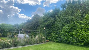 A well-maintained garden with a lawn, a wooden fence, and a variety of plants and flowers.