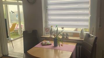 Ein Essbereich mit Tisch, Stühlen, einer Uhr und einem Fenster mit Jalousien.