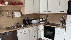 A modern kitchen with white cabinets, a dishwasher, a stove, and various kitchen utensils.