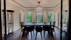 A dining area with a large table and chairs, a chandelier, and large windows offering a view of greenery. - Apartment 3 - Edersee time out (Edertal)