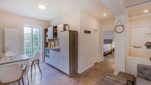 A modern kitchen with white cabinets, a wooden countertop, and a dining area with a table and chairs. - Apartment 3 - Edersee time out (Edertal)