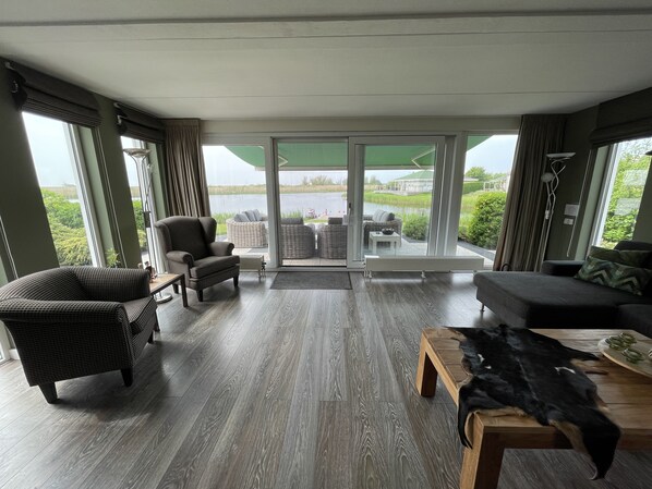 A spacious living room with a large sliding glass door leading to a balcony, furnished with wicker chairs and a sofa.