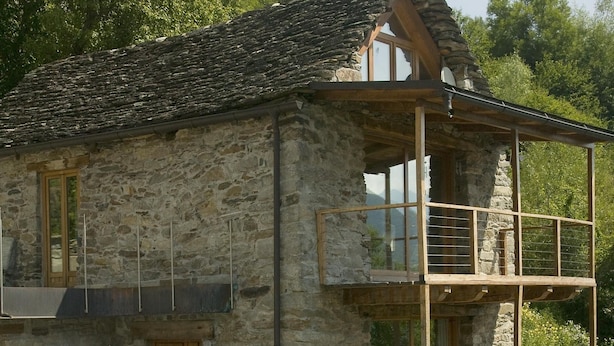 Un bâtiment en pierre doté d’un balcon en bois et d’un escalier menant à un deuxième étage.