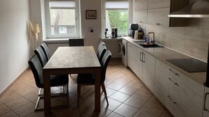 A compact kitchen with a dining table, chairs, a washing machine, and a built-in oven.