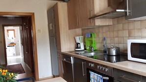 Une cuisine avec des meubles de rangement en bois, un four à micro-ondes, un évier et une cuisinière.