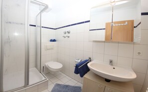 Ein Badezimmer mit Dusche, Toilette, Waschbecken und Spiegel.