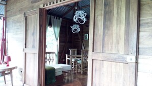 Eine Holzhütte mit offener Tür, die in einen Essbereich mit Tisch und Stühlen führt.