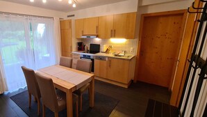 Cocina compacta con armarios de madera, una mesa de comedor y vistas a través de la ventana.