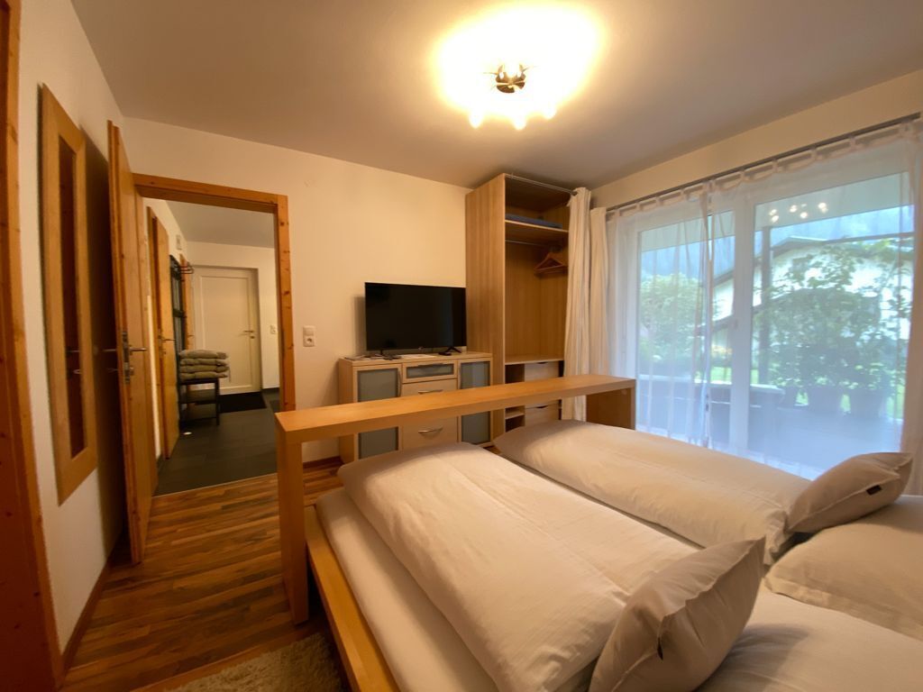 A bedroom with a wooden bed, a television, and a walk-in closet.
