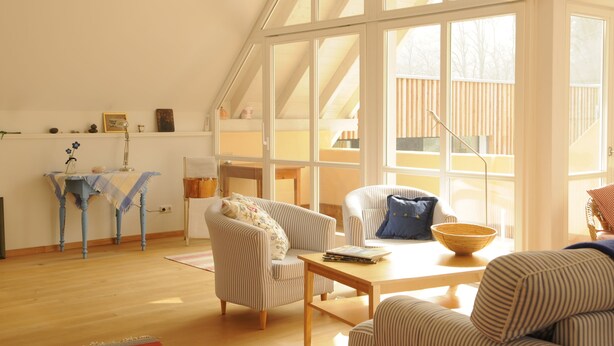 A spacious living room with a high ceiling, large windows, and a wooden floor. - Exclusive vacation apartment | dream location at the foot of the Alps | suitable for allergy sufferers (Füssen)