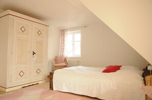 Une chambre à coucher avec un lit, une armoire, une chaise et une fenêtre.