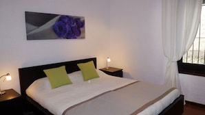 A neatly made bed with green pillows, a bedside lamp, and a framed picture on the wall. - Apartment in a beautiful, quiet location with stunning panoramic views across the sea (Velilla-Taramay)