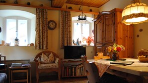 A cozy living room with a fireplace, wooden furniture, and a television. - Romantic holiday home (Dörflis)