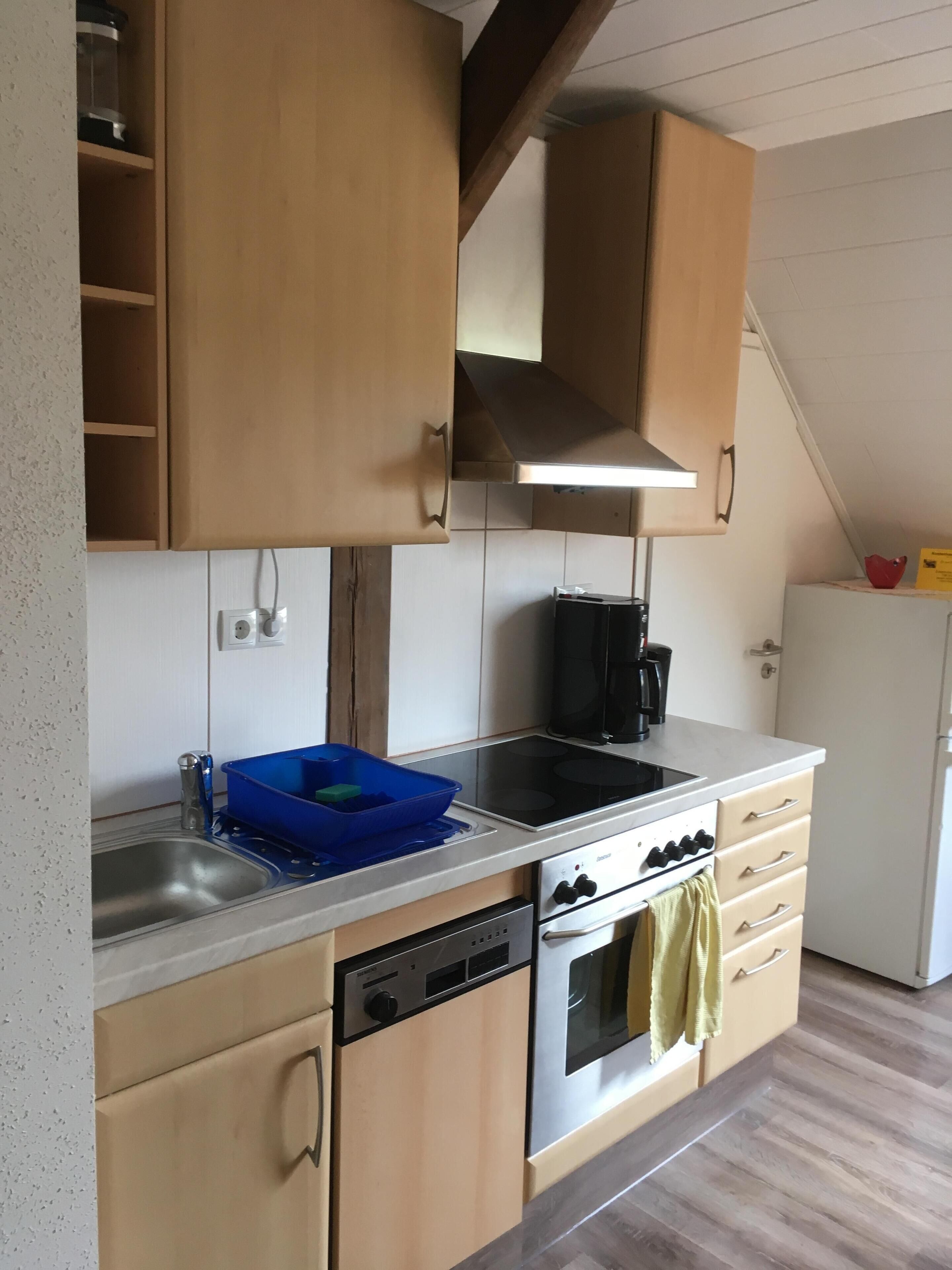 A kitchen with wooden cabinets, a stainless steel sink, a dishwasher, an oven, and a coffee maker.