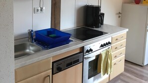 A kitchen with wooden cabinets, a stainless steel sink, a dishwasher, an oven, and a coffee maker. - Holidays with pony rides, WiFi, TV, dishwasher, oven (Butjadingen - Stollhamm)