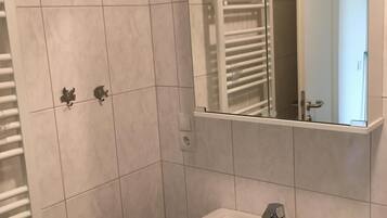 Ein Badezimmer mit einem weißen Waschbecken, einem Spiegel und einem Handtuchhalter.