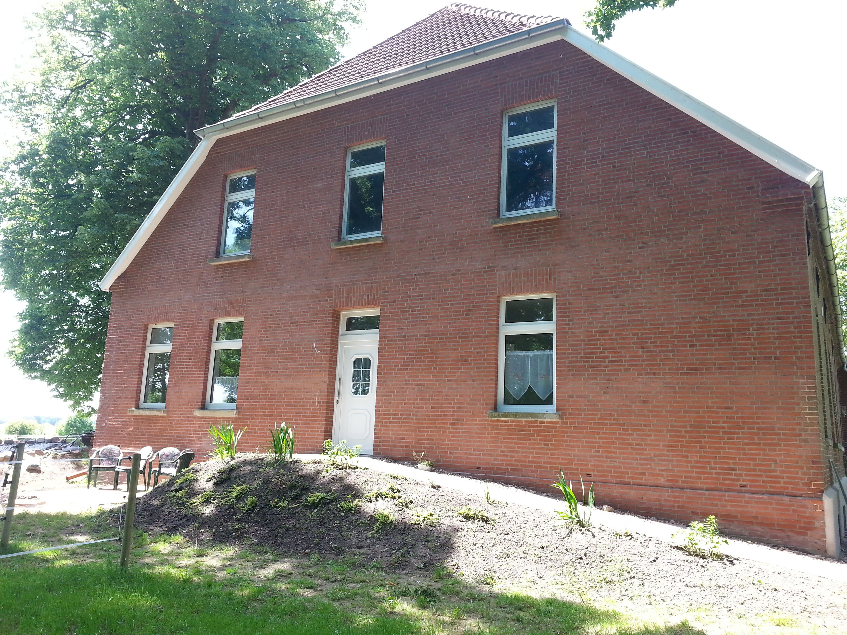 Ein rot backsteinsches Gebäude mit einer weißen Tür und mehreren Fenstern.