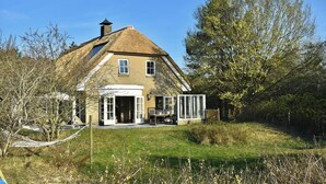 A house with a thatched roof, a large open patio, and a garden. - Large, detached cottage, 5 stars, near the beach, beautiful view. (Buren)